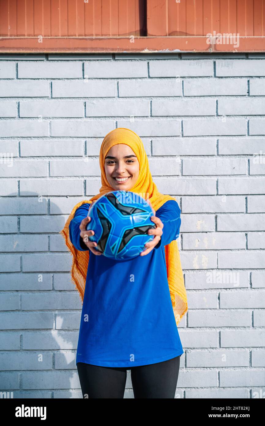 Femme arabe souriante qui dépasse les mains avec le ballon Banque D'Images