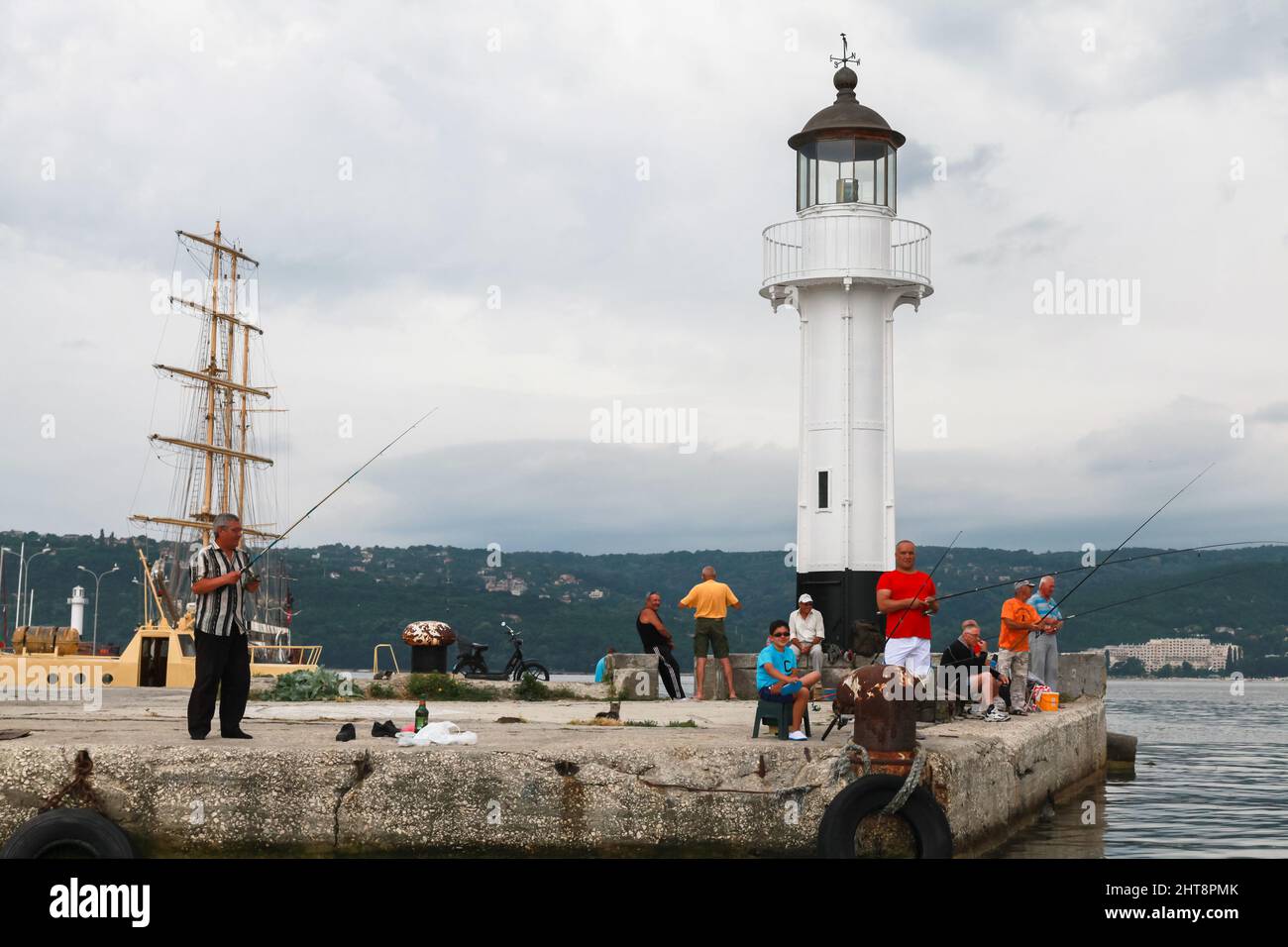 Varna, Bulgarie - 16 juillet 2014: Les pêcheurs sont près de la tour blanche de phare dans le port de Varna Banque D'Images