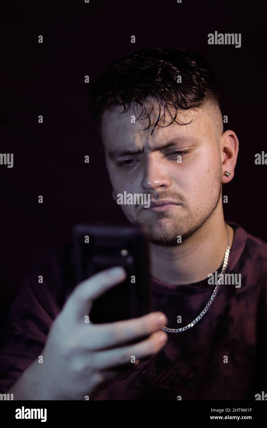 Photo verticale d'un homme contrarié lisant des informations sur son smartphone Banque D'Images
