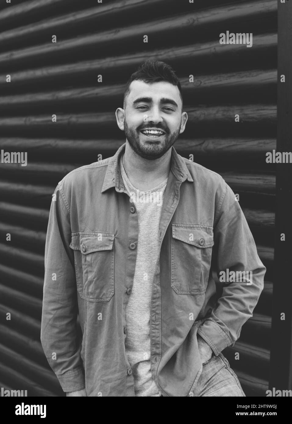 Prise de vue verticale en niveaux de gris d'un homme caucasien souriant portant une veste à Vigo, en Espagne Banque D'Images