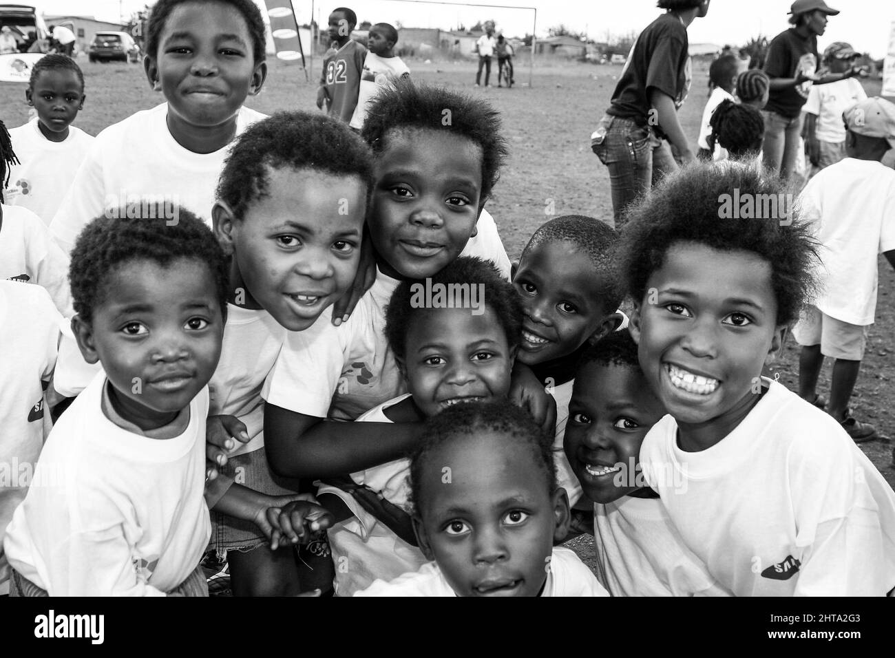 Photo en niveaux de gris de jeunes enfants africains posant pour une photo sur un terrain de jeu scolaire Banque D'Images