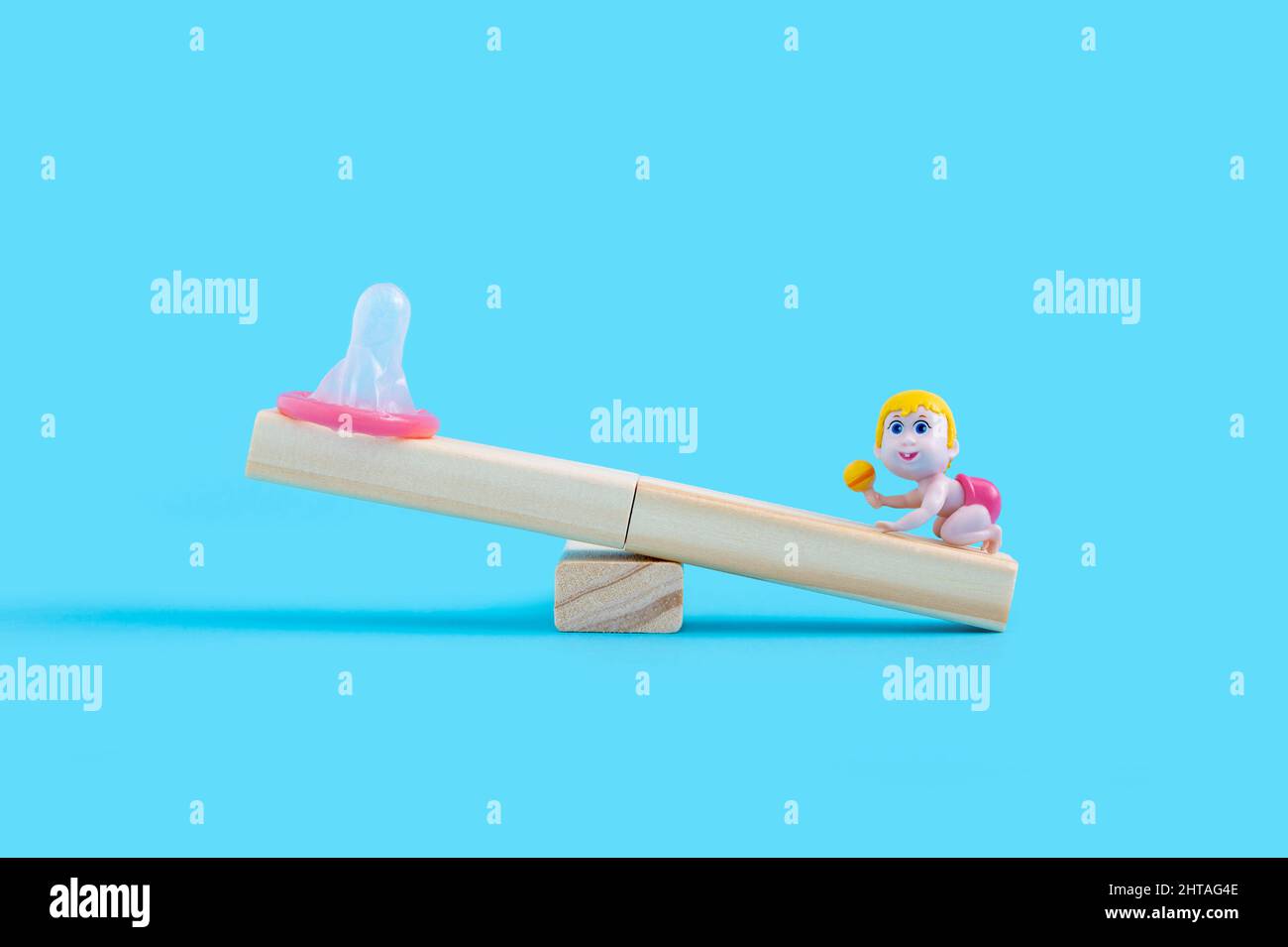 Concept de grossesse avec condom et poupée bébé sur la seesaw en bois Banque D'Images