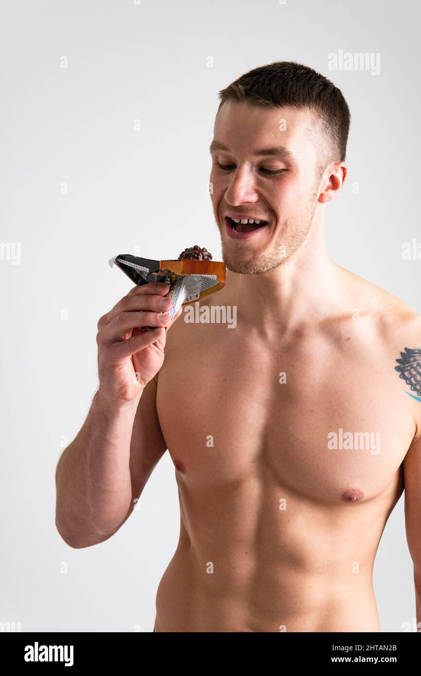 L'homme mange la barre de protéines sur fond blanc isolé jeune snack sain, tenant l'athlète souriant bien-être, calorie isolée. Exercice en plein air femelle Banque D'Images