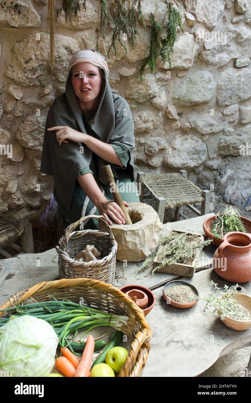 Une actrice présente une femme du premier siècle préparant un repas au musée en plein air du village de Nazareth, en Israël. Banque D'Images