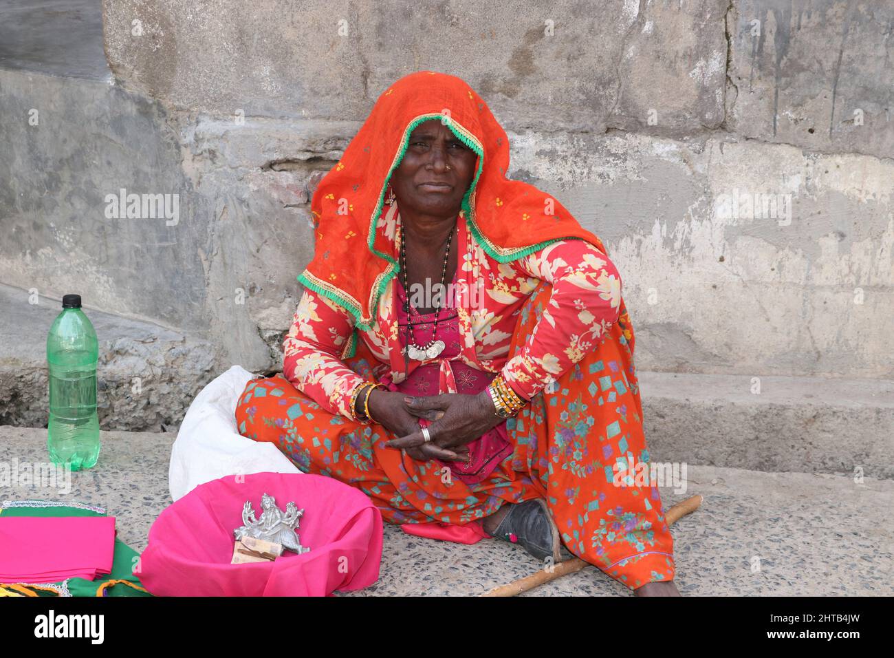 une femme mendiante assise sur la route dans une robe colorée. Banque D'Images