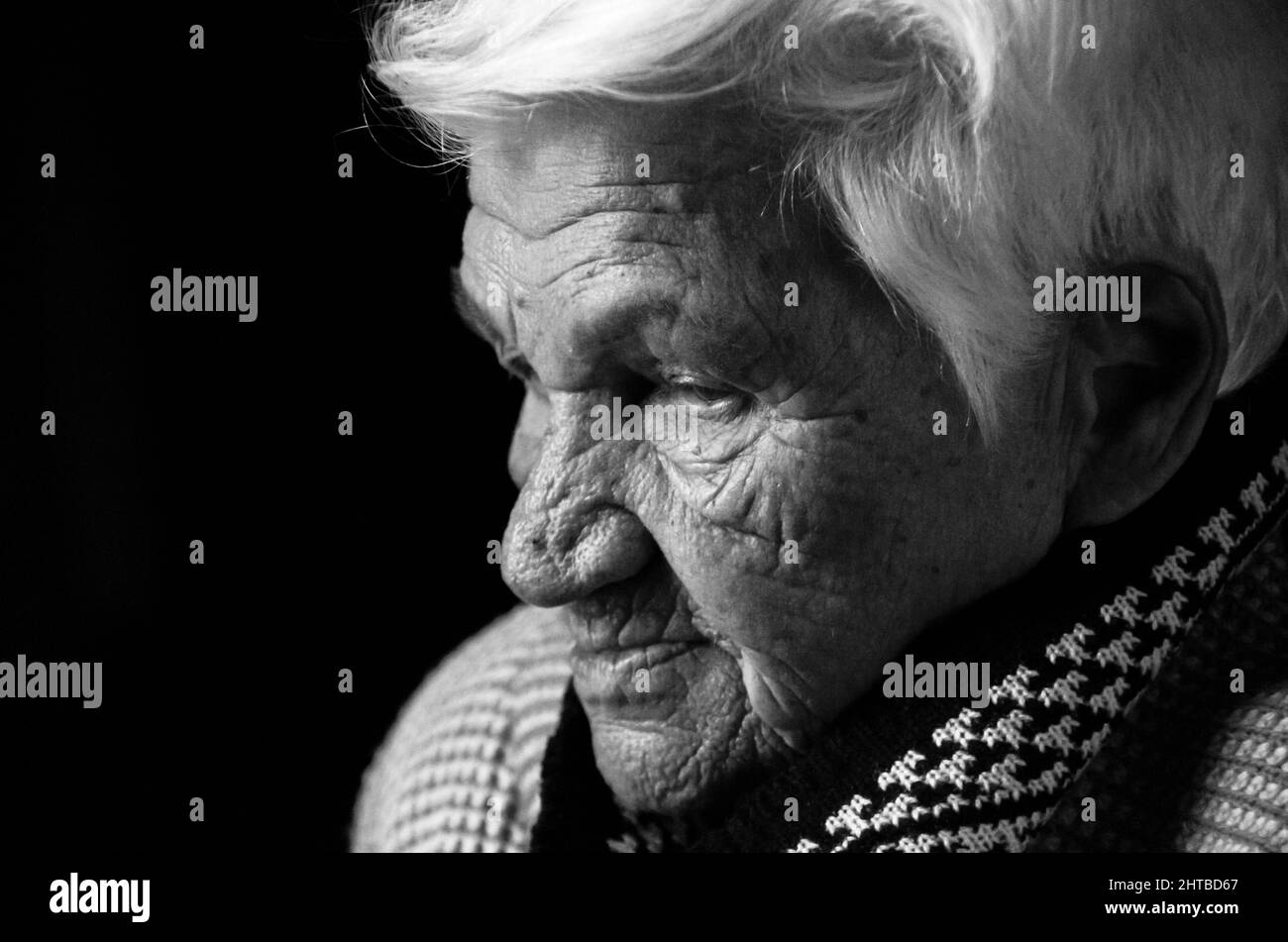 Portrait d'une femme âgée sérieuse sur fond noir. Photo en noir et blanc. Banque D'Images