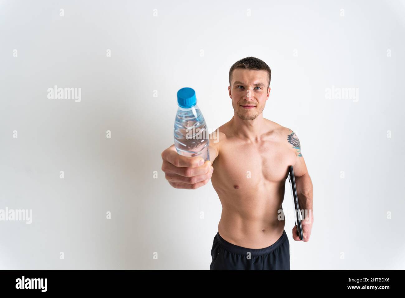 La forme physique à l'eau potable est pompée avec une serviette sur un fond blanc isolé de sport d'entraînement fort homme tenant, break cardio. Power Banque D'Images
