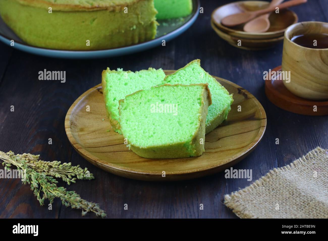 Gâteau au mousseline de Bolu pandan ou de Pandan, servi avec du thé sur fond de bois sombre. Mise au point sélective. Banque D'Images
