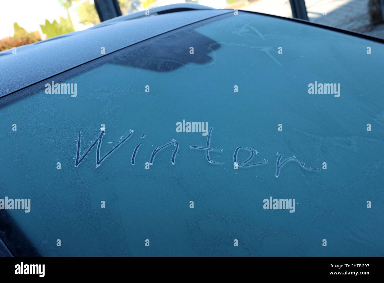 Vue d'une inscription bleue « Winter » sur une fenêtre de voiture gelée Banque D'Images