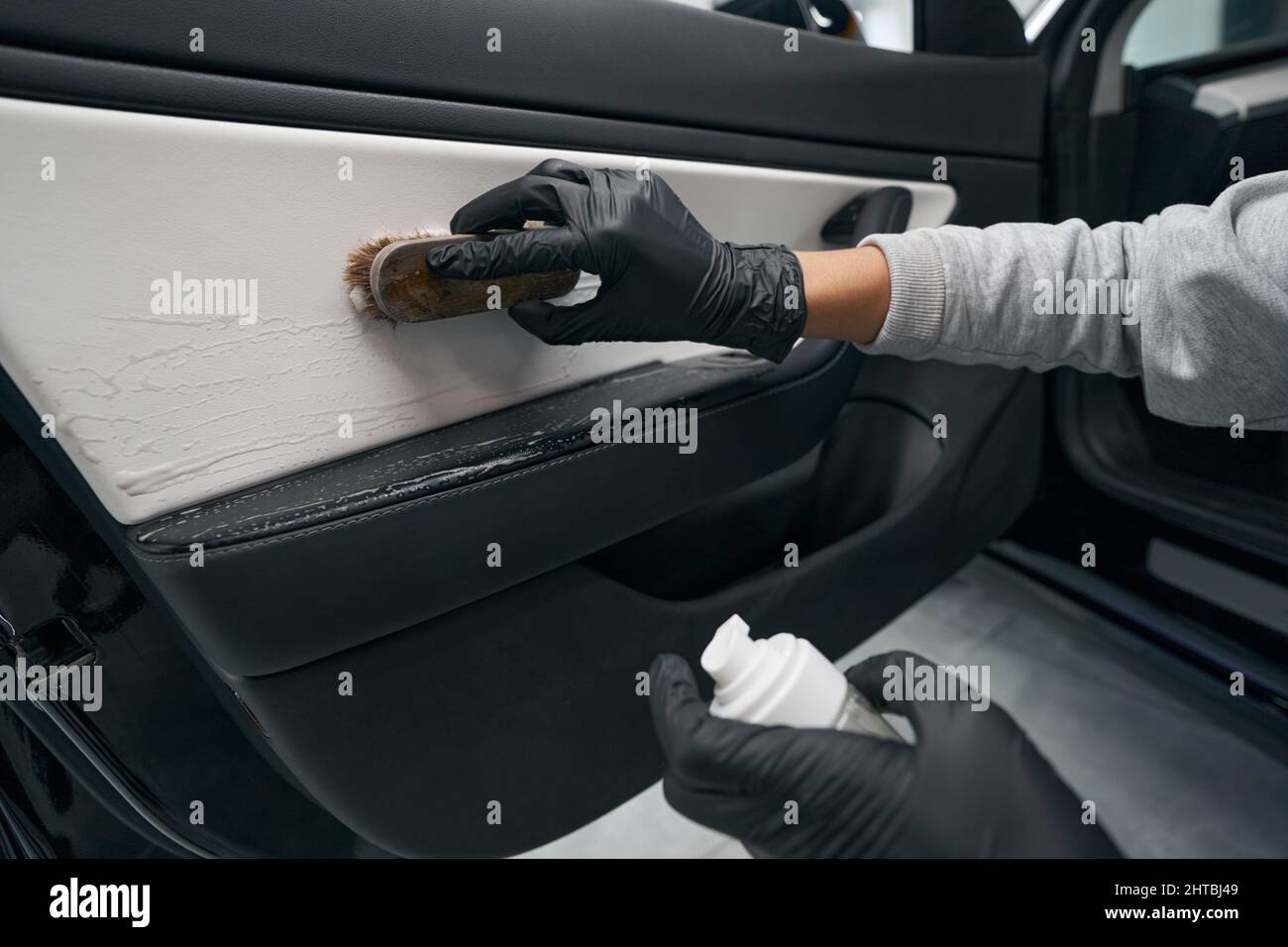Professionnel utilisant une brosse et un agent de lavage pendant les détails Banque D'Images