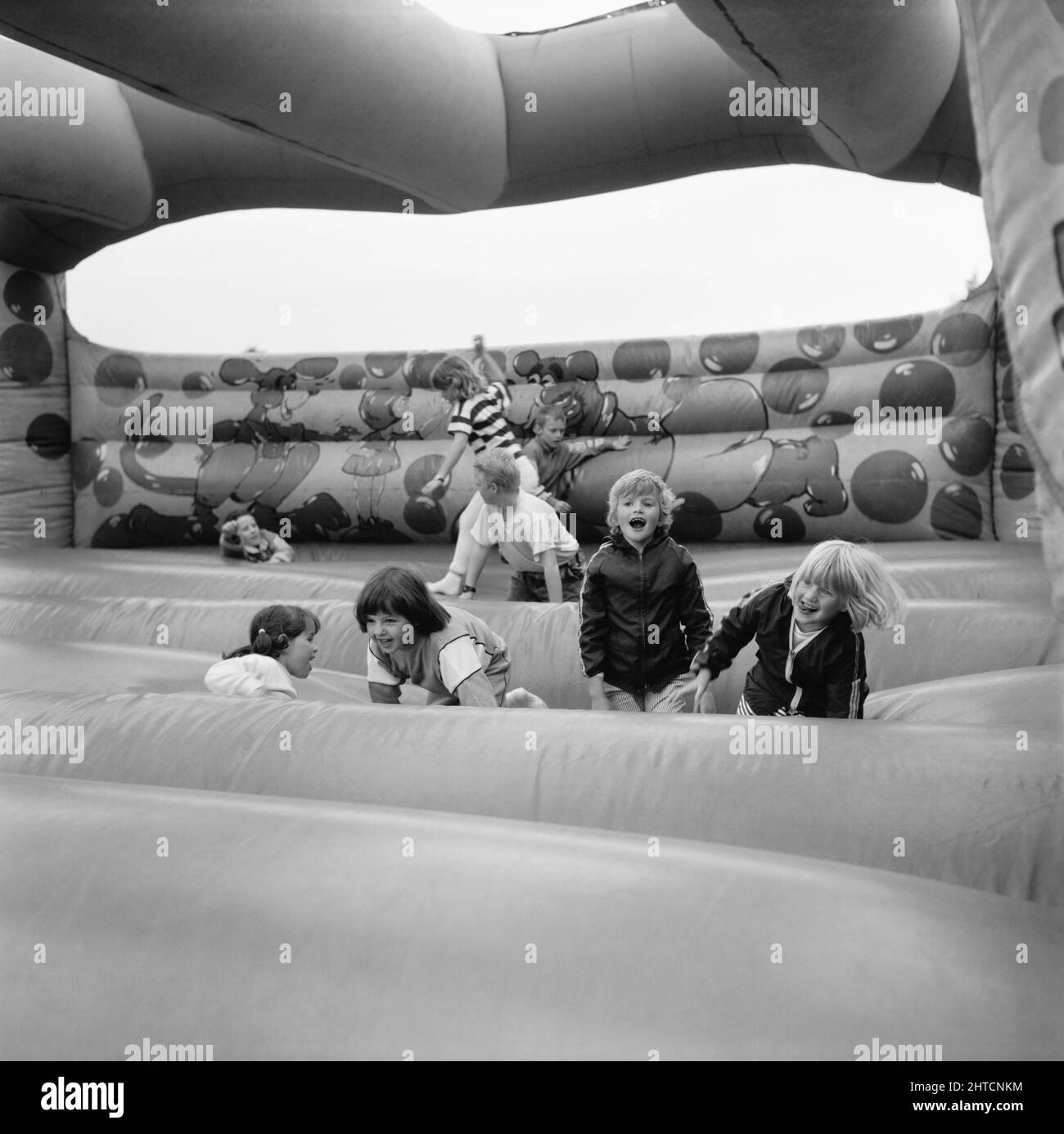 Laing Sports Ground, Rowley Lane, Elstree, Barnett, Londres, 11/06/1988. Enfants jouant sur le château de Bouncy à la Journée de la famille 1988 au terrain de sport de Laing. Les attractions de la Journée de la famille de cette année-là incluent : une parade de voitures d'époque, des tours en hélicoptère, des courses de plaques, des stands, une compétition de style « c'est un Knockout », des tournois de tennis et de football à six. L'événement a été ouvert par John Conteh, ancien champion mondial de poids lourd léger et s'est terminé par un barbecue et une discothèque. Banque D'Images
