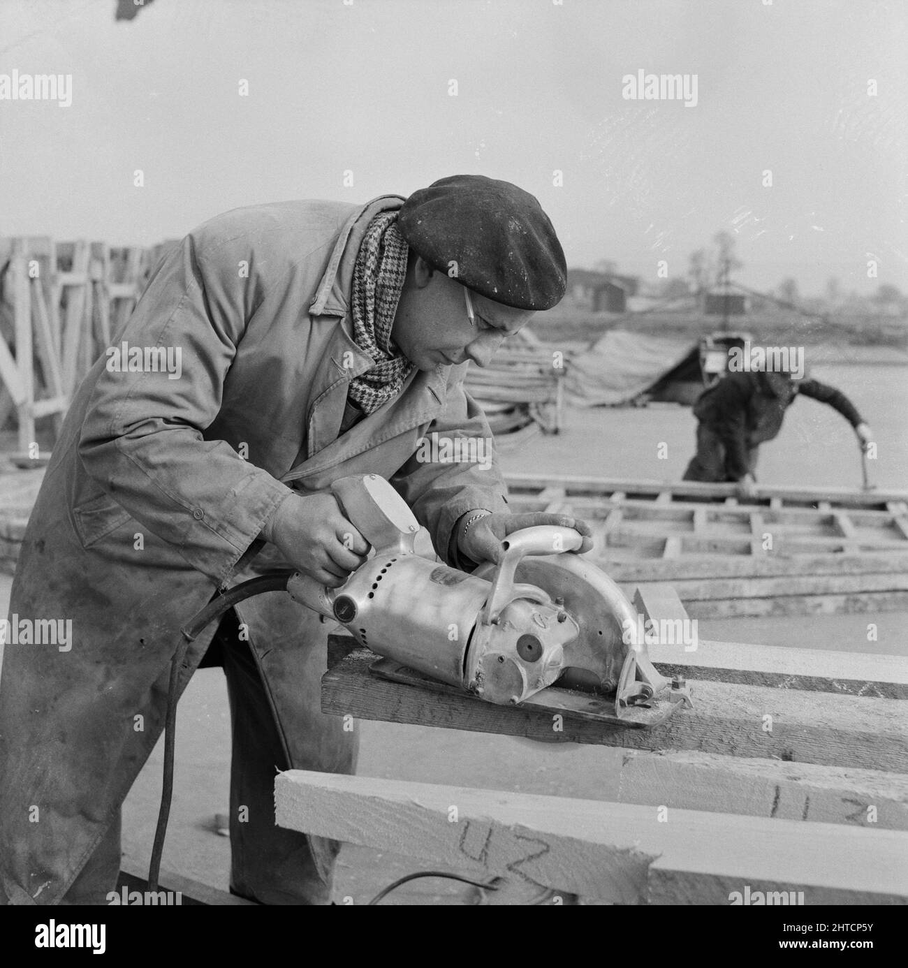 RAF Gaydon, Gaydon, Stratford-on-Avon, Warwickshire, 11/03/1953. Un ouvrier utilisant une scie circulaire électrique pour couper du bois pour la construction de bâtiments à Gaydon Airfield. Les travaux de construction d'une nouvelle piste à l'aérodrome de Gaydon ont commencé au début de 1952. Ce contrat a été suivi d'un deuxième contrat pour la construction de plus de 100 bâtiments du Ministère de l'air et de l'Easiform, et de 23 refuges de Nissen. Banque D'Images