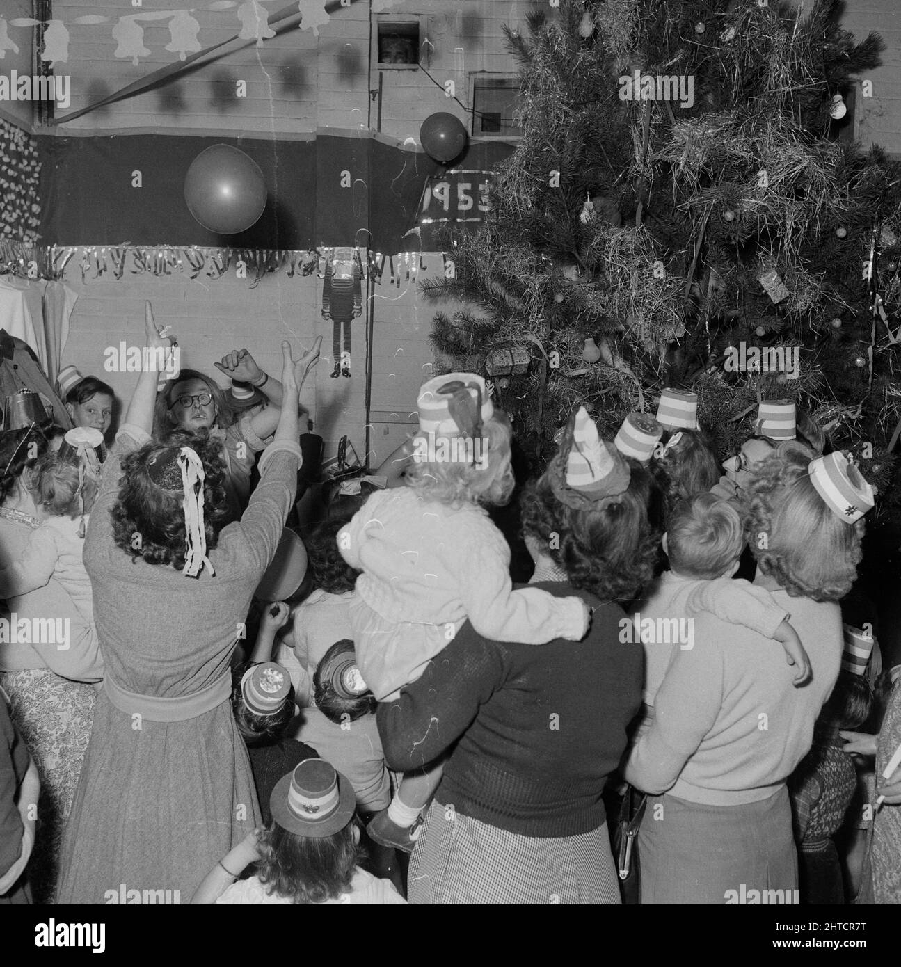 Thurleigh Airfield, Thurleigh, Bedfordfordshire, 19/12/1953. Parents et enfants jouant avec des ballons lors d'une fête d'enfants. Cette photo montre une fête d'enfants organisée par le personnel du bien-être social de Laing et des membres du Comité pour les enfants du personnel travaillant sur le projet d'aérodrome de Thurleigh. La fête a eu lieu au Camp Theatre et comprenait des clowns, des jeux, un spectacle cinématographique, des cadeaux du Père Noël et du thé pour soixante enfants. Banque D'Images