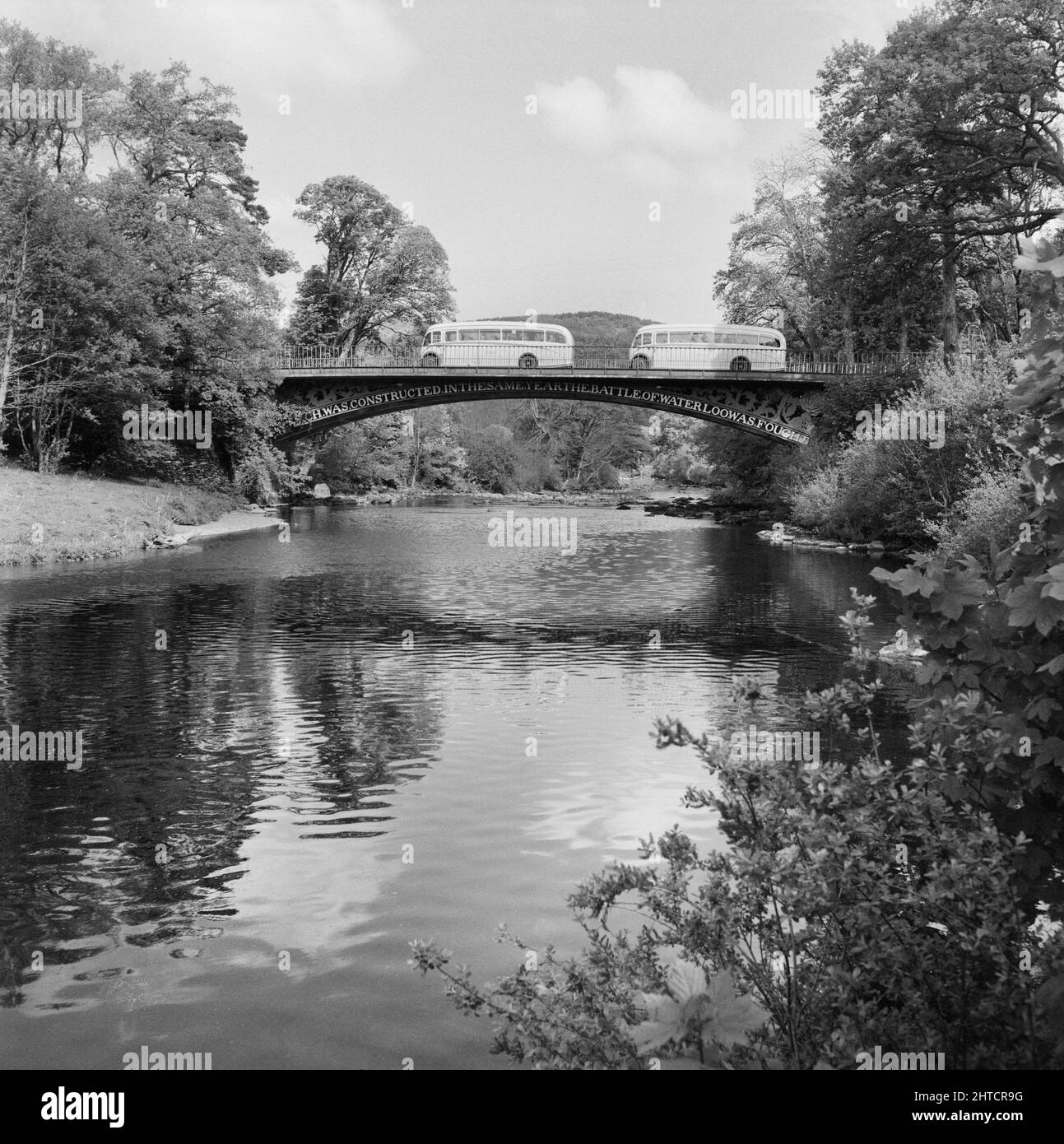 Waterloo Bridge, Betws y Coed, pays de Galles, 15/05/1954. Deux cars franchissent le pont Waterloo lors d'un voyage du personnel de Laing à Llandudno. En 1947, après une pause de sept ans, Laing avait ressuscité ses « sorties de la région » pour le personnel et leurs familles, avec des voyages qui ont lieu en mai et juin. En 1954, sept sorties ont été prévues sur cinq semaines en mai et juin. Ce voyage a été fait pour le personnel et leurs familles du nord du pays de Galles et du nord-ouest de l'Angleterre. Banque D'Images