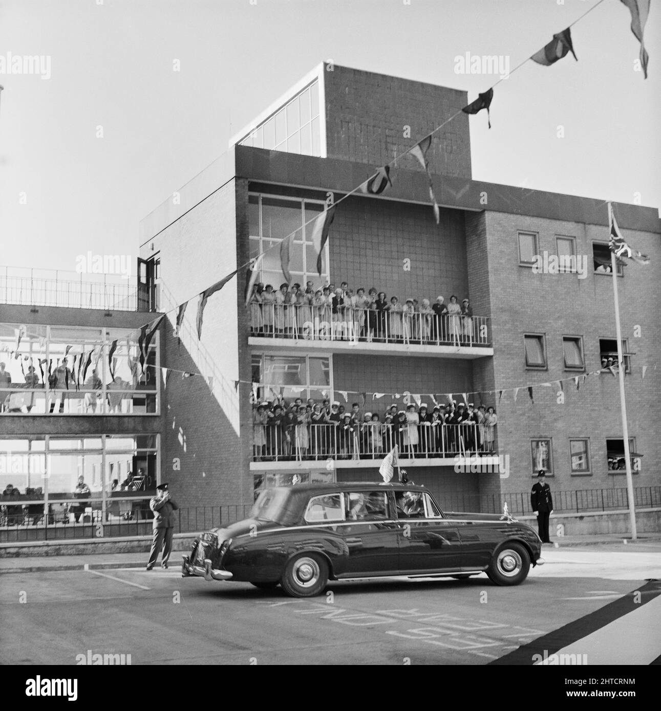 West Cumberland Hospital, Homewood Road, Homewood, Whitehaven, Copeland, Cumbria, 21/10/1964. Le personnel de l'hôpital croque des balcons à l'hôpital de West Cumberland pour déferrer la reine mère alors qu'elle part dans sa voiture officielle après la cérémonie d'ouverture. Banque D'Images