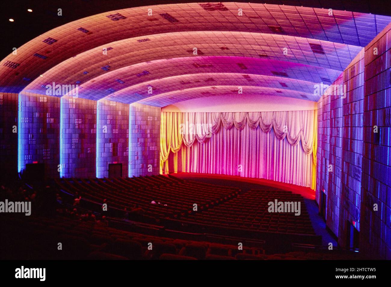 Empire Cinema, Leicester Square, Cité de Westminster, Londres, 1986. L'auditorium de l'écran 1 dans l'Empire Cinema. L'Empire Theatre a ouvert ses portes en 1884 et a été conçu par Thomas Verity. Sa façade, son entrée et son auditorium ont été rédéveloppés à la fin de 19th et au début de 20th siècles. Entre 1928 et 1961, l'auditorium avait 3300 sièges. Après 1962, lorsque l'intérieur a été redessiné par George Coles, les anciens stands sont devenus une salle de danse, plus tard un casino. En 1980s, le cinéma a été converti en trois écrans: L'écran original 1 pouvait accueillir 1330 personnes, le Ritz Cinema adjacent est devenu crier Banque D'Images