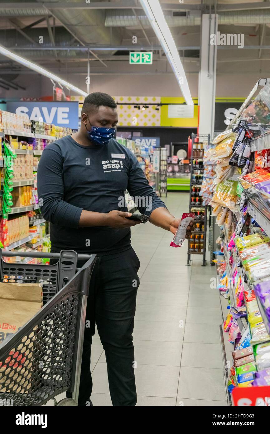 Cape Town, Afrique du Sud - 9 septembre 2021 : un membre du personnel cueille des produits à partir de l'étagère pour un service de livraison express à domicile Banque D'Images