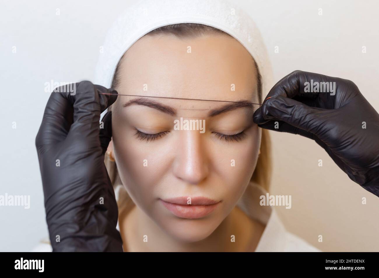 Tatouage de sourcil .permanent masque de maquillage de sourcil applique le contour avec un fil sur le sourcil du client Banque D'Images