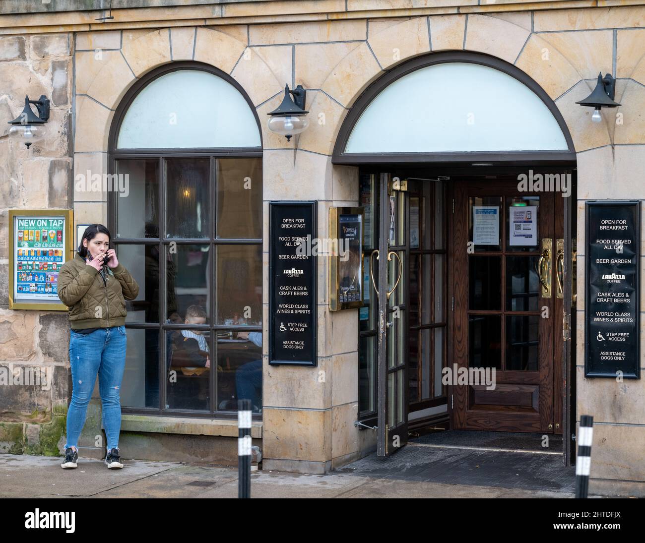 25 février 2022. High Street, Elgin, Moray, Écosse. C'est une femme qui est allée à l'extérieur du Pub pour avoir une fumée tout en bavardant sur son téléphone mobile Banque D'Images