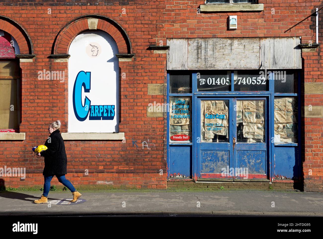 Femme passant devant un entrepôt de tapis à Thorne, dans le sud de Yorkshirte, en Angleterre Banque D'Images