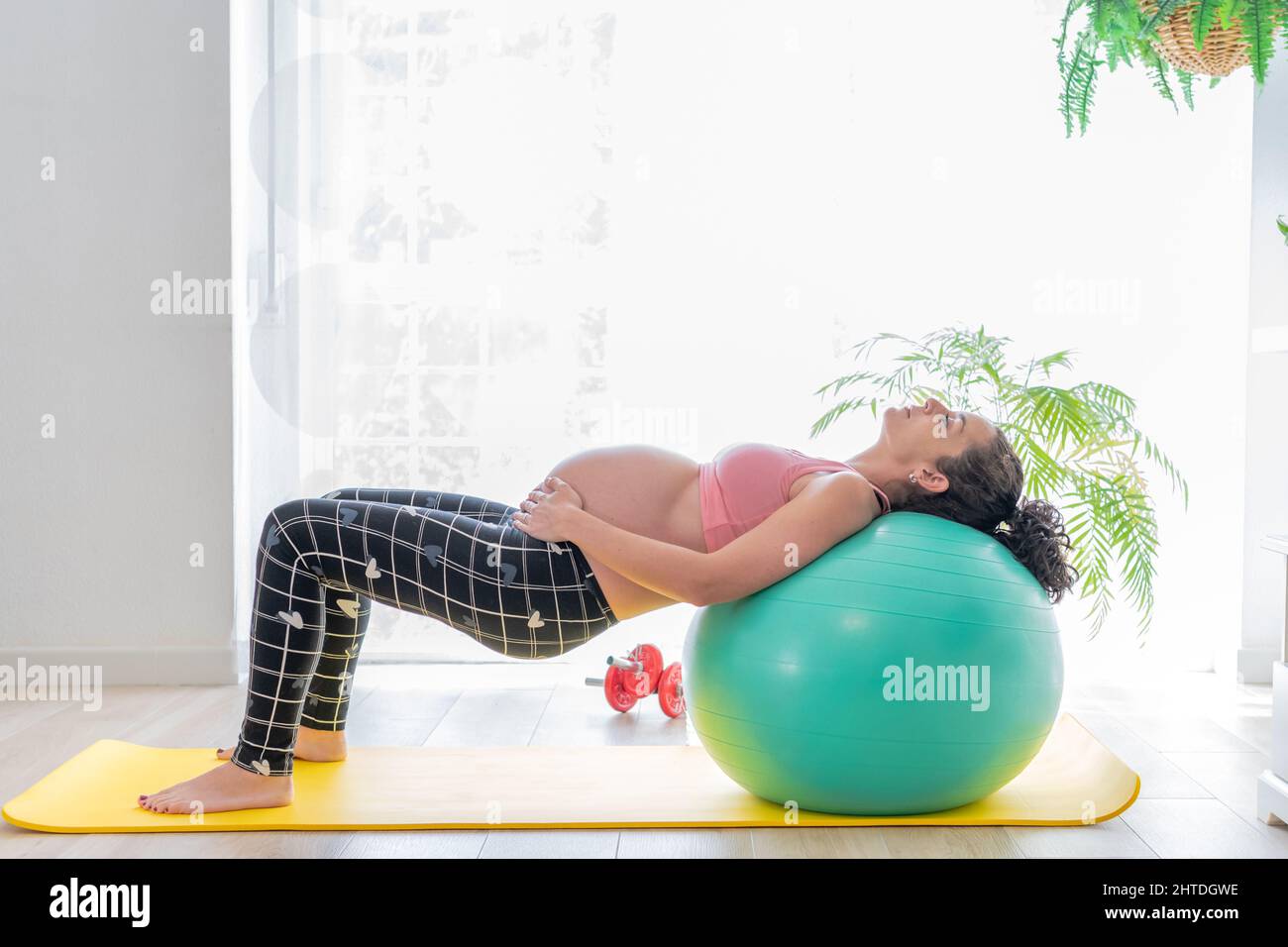 une jeune femme enceinte qui se penche sur un ballon de fitness fait des  exercices pour renforcer son plancher pelvien et son dos pendant la  grossesse. soins du corps et santé Photo