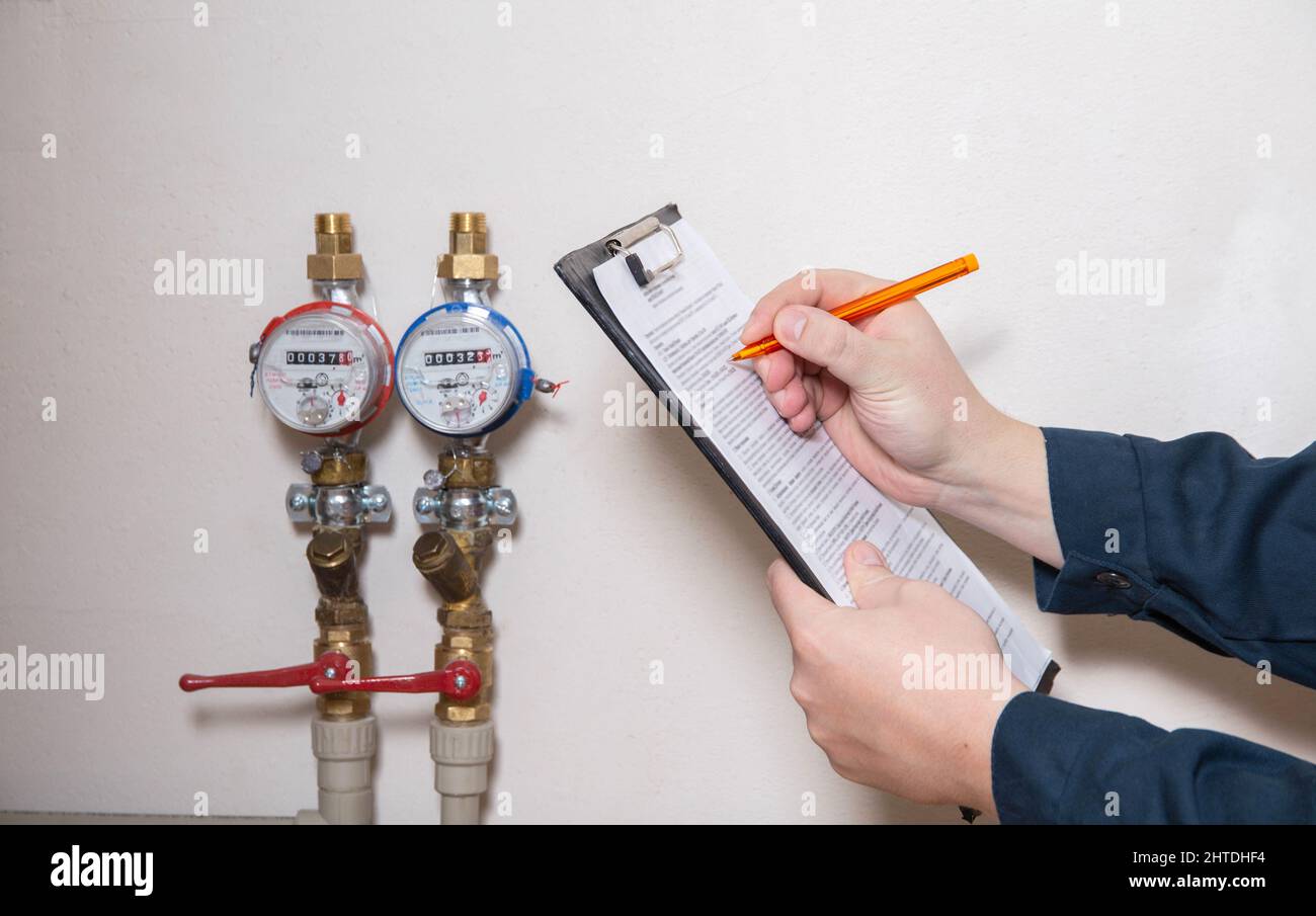 Un homme écrit les relevés des compteurs d'eau avec un stylo sur papier. Le concept de payer pour les services publics. Augmentation du prix par mètre cube d'eau, fermer Banque D'Images