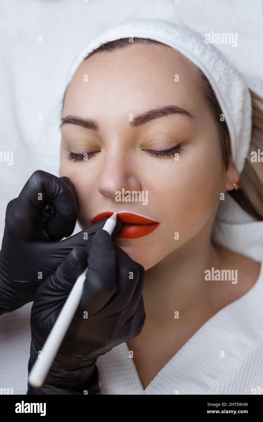 Jeune femme avec maquillage permanent sur ses lèvres dans un salon de  cosmétologues. Tatouage de maquillage permanent. Dessinez une ligne avec un  crayon blanc à lèvres Photo Stock - Alamy