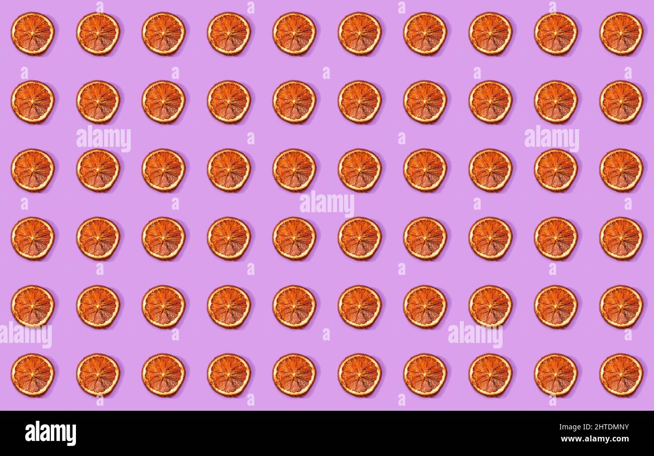 Arrangement régulier de tranches d'orange disséquées sur une surface violette. Banque D'Images