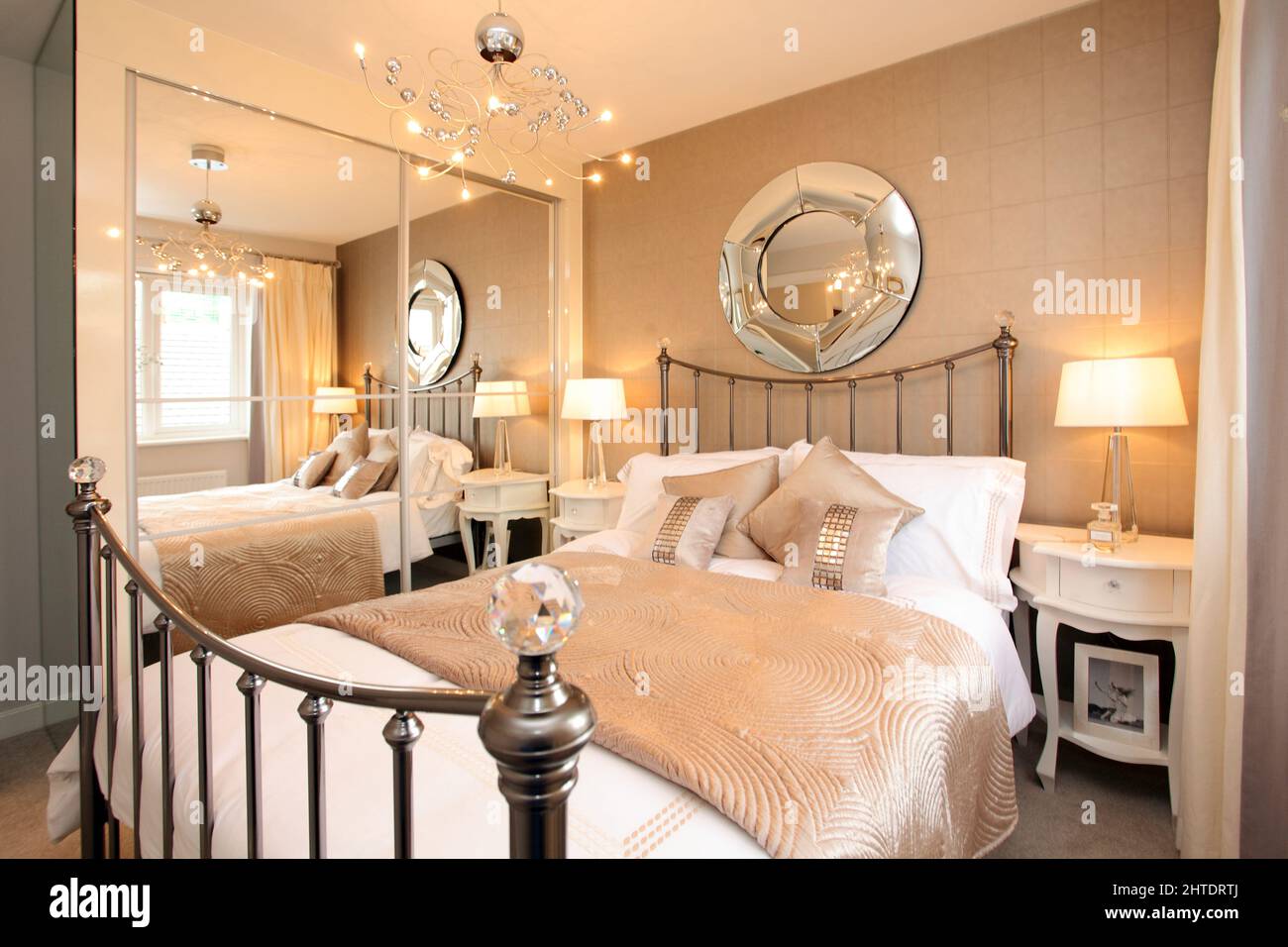 Chambre moderne dans une maison neuve, couvre-lit matelassé, tête de lit en laiton, beige blanc crème couleur neutre Banque D'Images