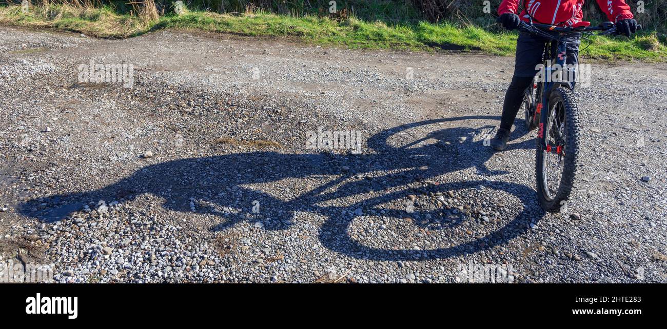 Le cycliste offroad prend un beureur qui jette une longue ombre sous le soleil de l'après-midi. Banque D'Images