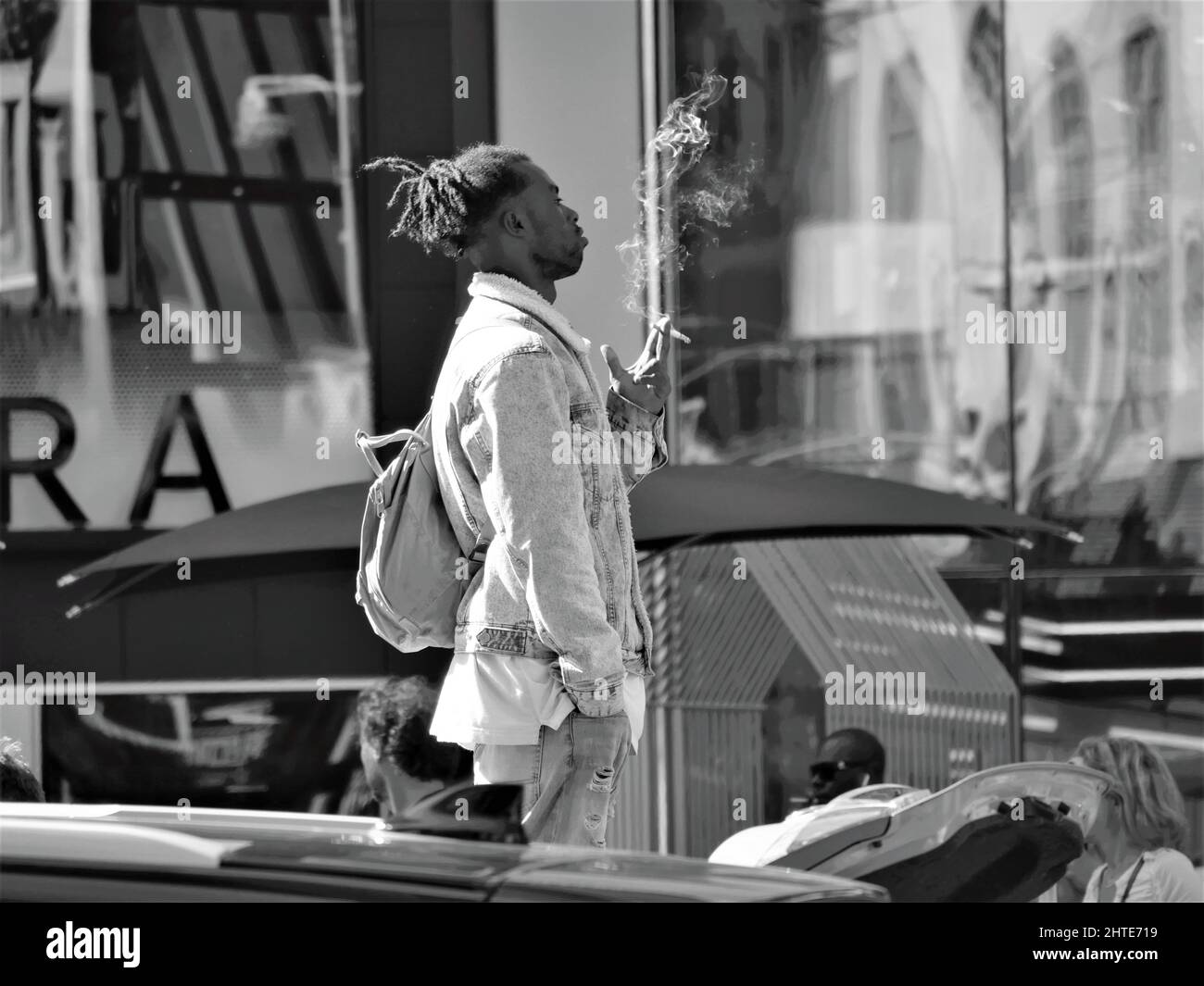 Échelle de gris d'un homme ayant une fumée tout en regardant la circulation près de Timesquare, New York City Banque D'Images
