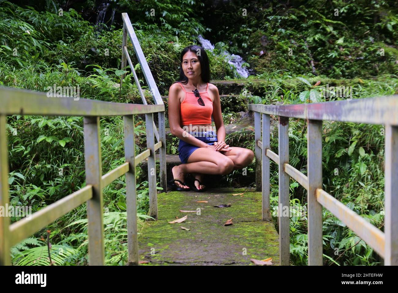Une dame joyeuse se posant assise près de la chute d'eau Gitgit à Bali, en Indonésie Banque D'Images