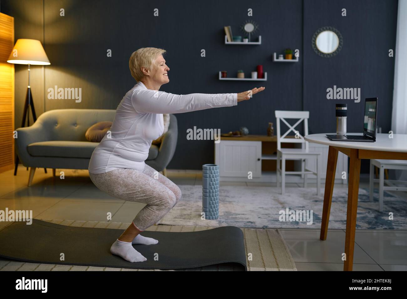 Femme âgée faisant des squats s'exerçant à la maison Banque D'Images
