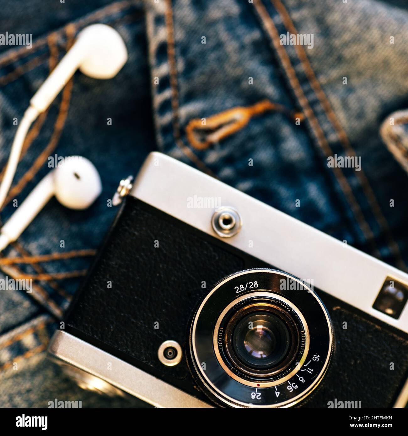 L'appareil photo et le casque avec fil blanc reposent sur l'arrière-plan du denim. Arrière-plan tendance des vêtements taille basse. Style rétro. Journée des photographes. Vue de dessus Banque D'Images