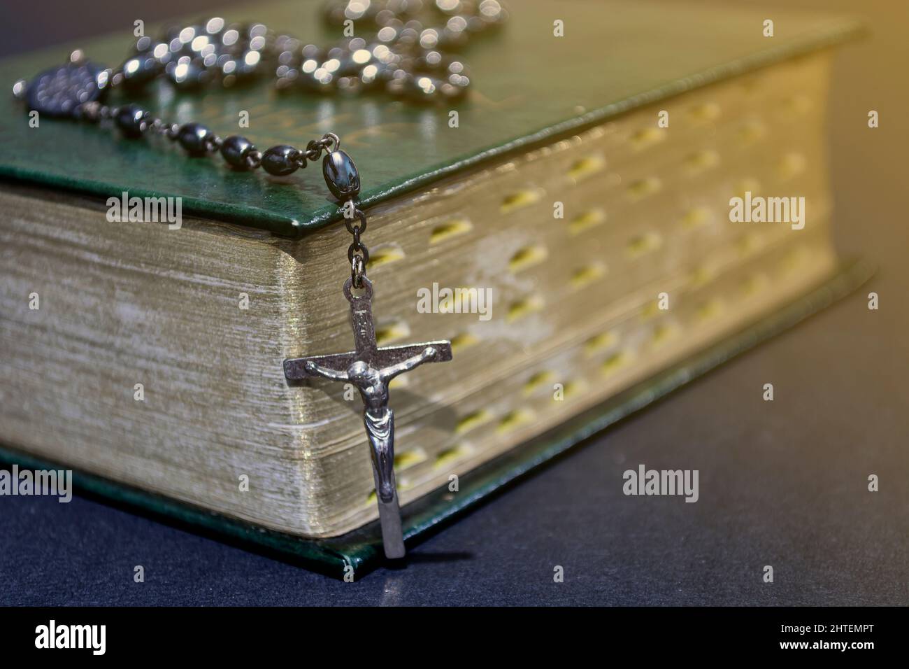 La croix sur la bible sur une table en bois avec lumière de fenêtre, ton vintage. Banque D'Images