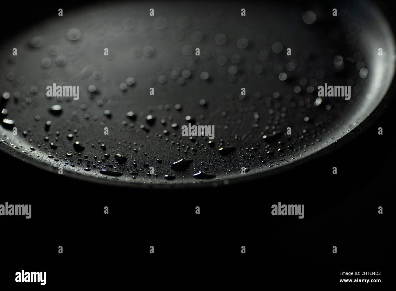 Fait partie d'une casserole vide en fonte de couleur noire avec des gouttes d'huile végétale. Gros plan. Arrière-plan sombre. Commencez la cuisson Banque D'Images