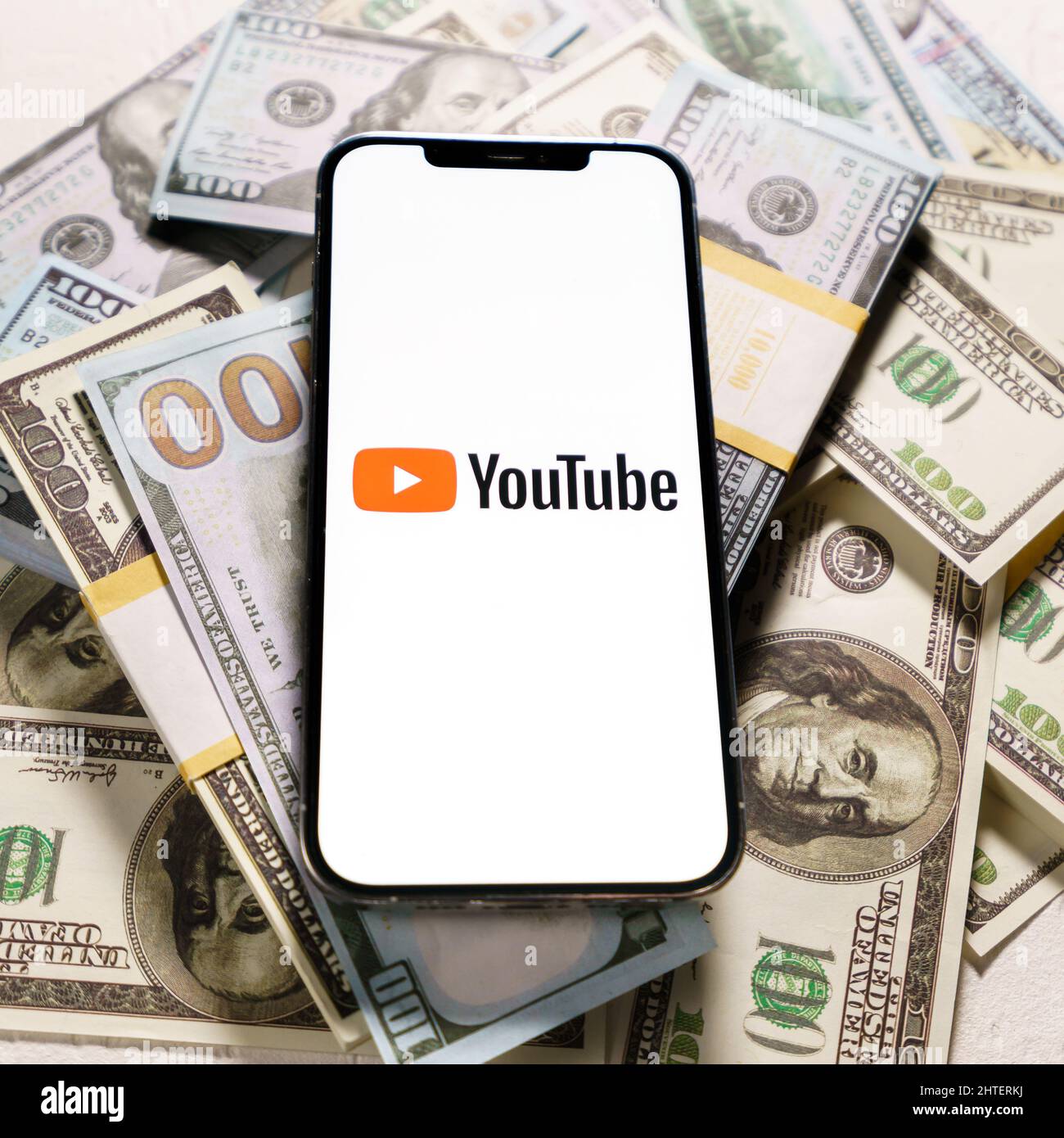 Berlin, Allemagne - 02 février 2022 : billets en dollars et logo YouTube à l'écran iPhone 12 Pro Max.YouTube est une application gratuite de partage de vidéos Banque D'Images