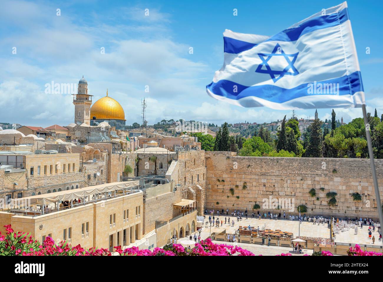 Un drapeau israélien souffle dans le vent tandis que les croyants orthodoxes juifs lisent la Torah et prient face au mur occidental, également connu sous le nom de mur de Wailing dans la vieille ville Banque D'Images