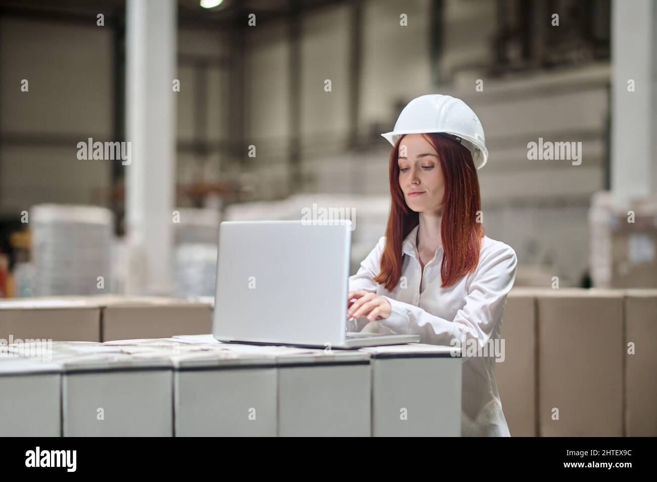 Femme travaillant sur un ordinateur portable à proximité d'un chargement empilé Banque D'Images