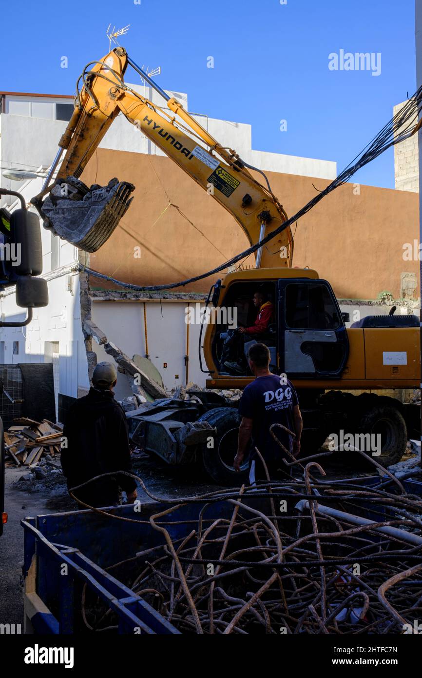 L'excaveur mécanique Hyundai soulève des décombres d'une maison de démolition sur des câbles électriques à Playa San Juan, Tenerife, îles Canaries, Espagne Banque D'Images