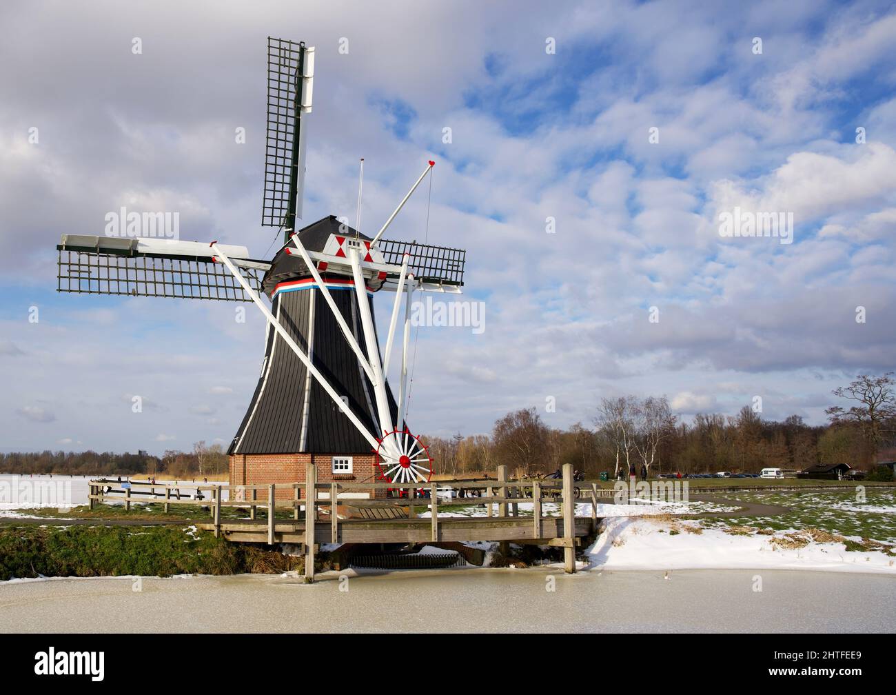 Moulin à vent hollandais typique en hiver avec eau gelée et ciel bleu avec quelques nuages Banque D'Images