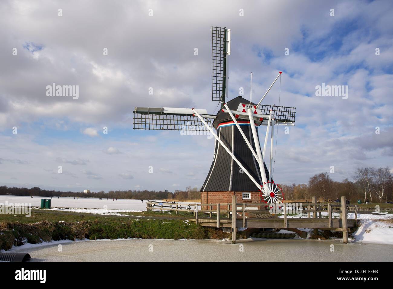 Moulin à vent hollandais typique en hiver avec eau gelée et ciel bleu avec quelques nuages Banque D'Images