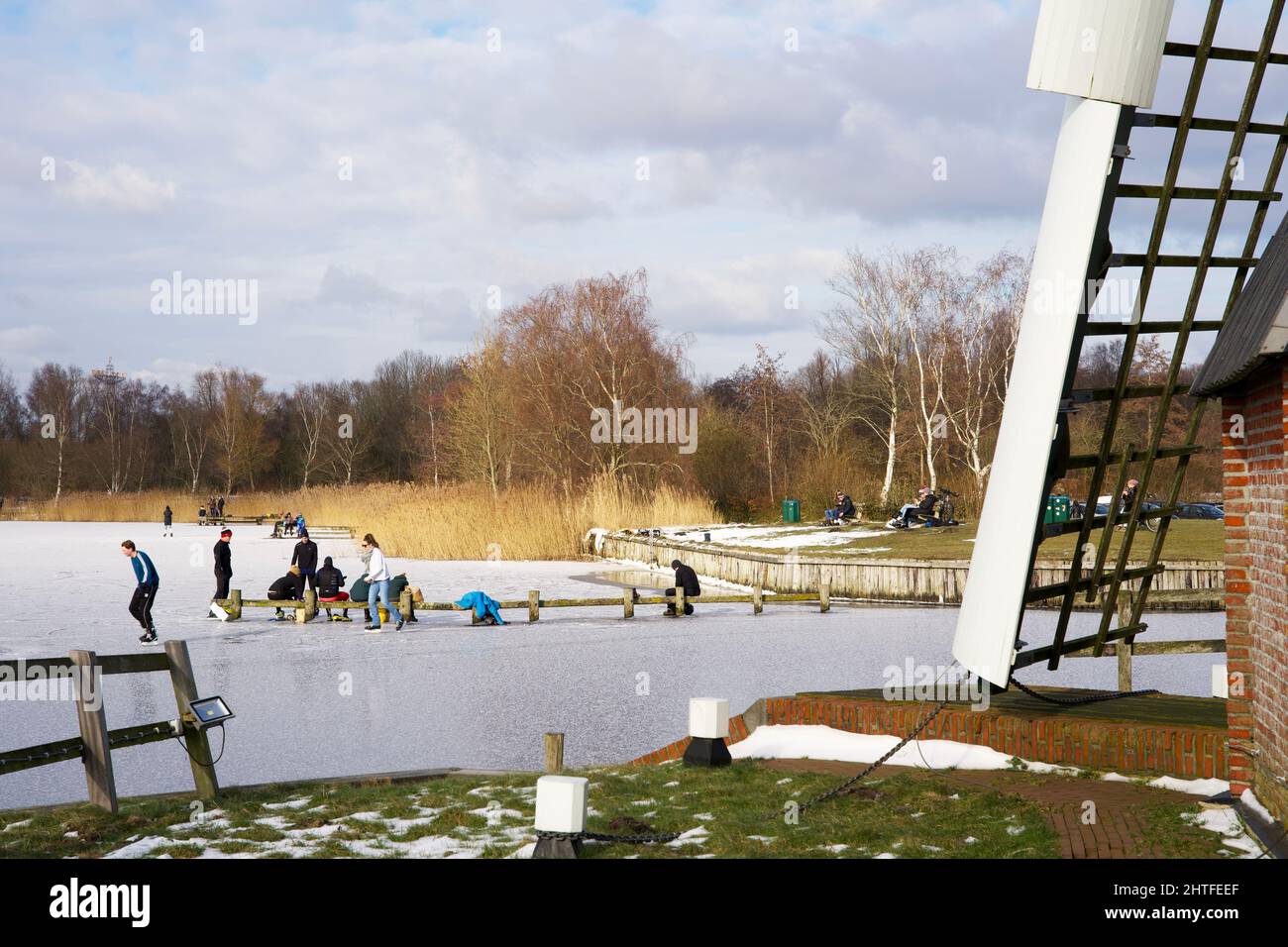 Moulin à vent hollandais typique en hiver avec eau gelée et ciel bleu avec quelques nuages Banque D'Images