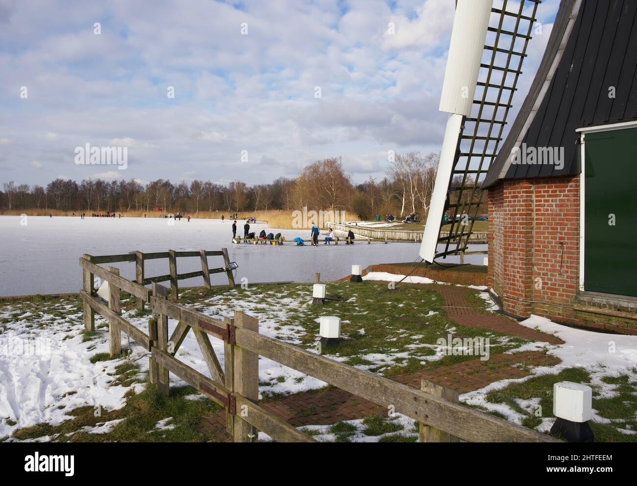 Moulin à vent hollandais typique en hiver avec eau gelée et ciel bleu avec quelques nuages Banque D'Images