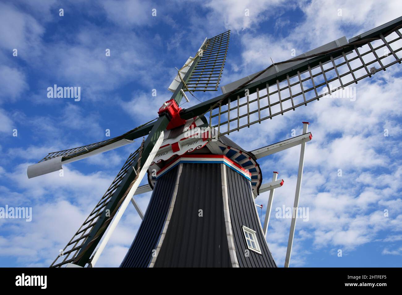 Moulin à vent hollandais typique en hiver avec eau gelée et ciel bleu avec quelques nuages Banque D'Images