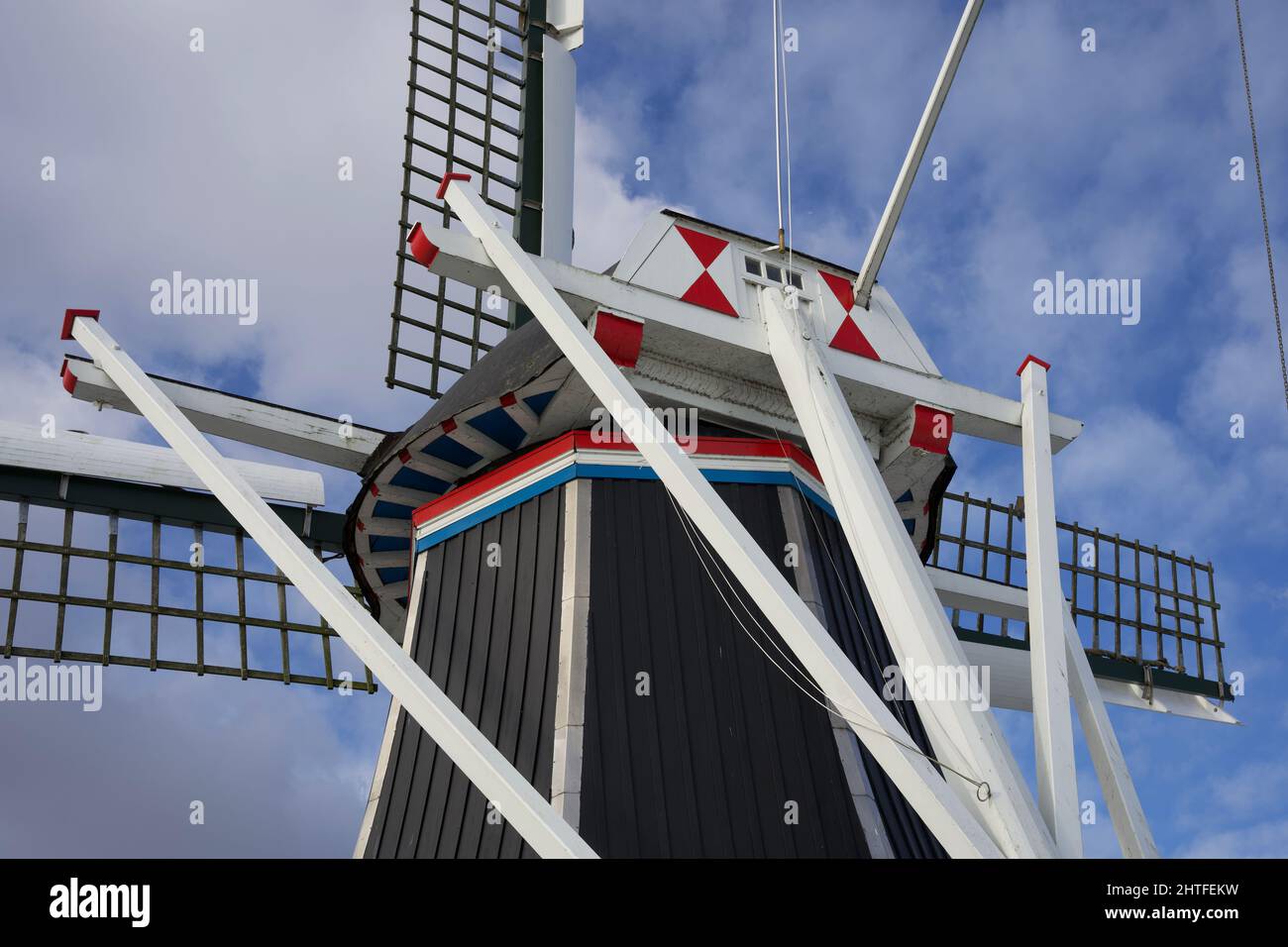 Moulin à vent hollandais typique en hiver avec eau gelée et ciel bleu avec quelques nuages Banque D'Images