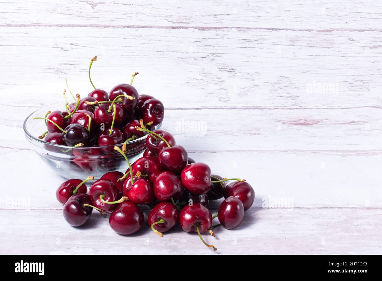 Cerises rouges délicieuses dans un bol en verre sur une table blanche Banque D'Images