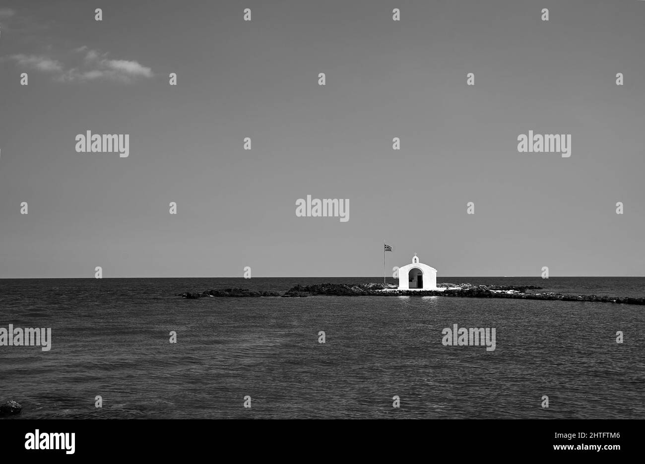 Une chapelle orthodoxe blanche sur un promontoire en pierre dans la ville de Georgioupoli sur l'île de Crète en Grèce, monochrome Banque D'Images