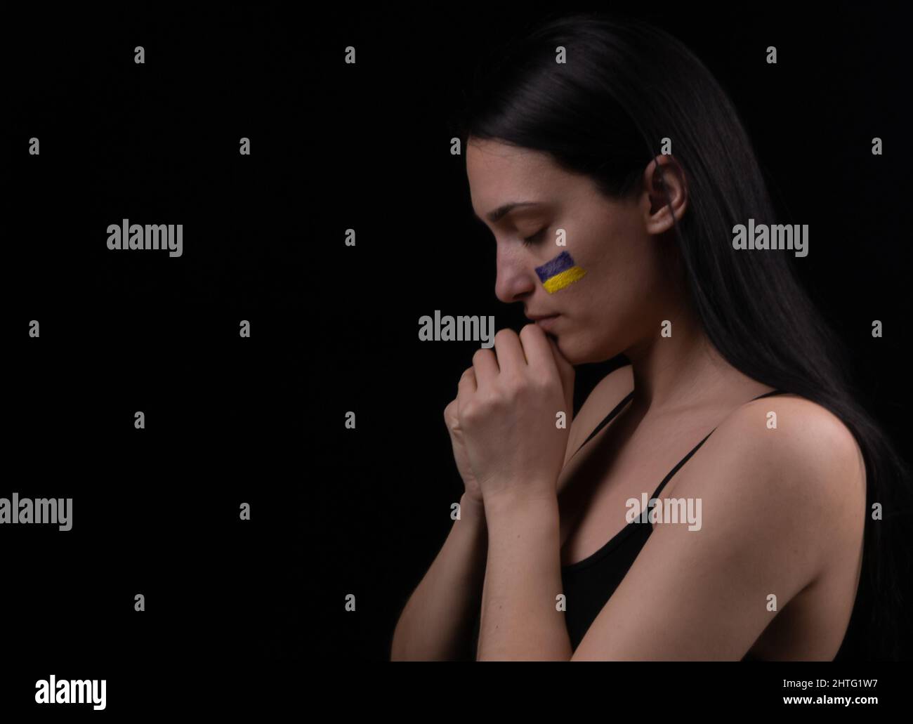 Portrait d'une femme ukrainienne sérieuse avec un drapeau ukrainien bleu et jaune sur sa joue. Le symbole de l'inviolabilité du peuple ukrainien. Ba foncé Banque D'Images