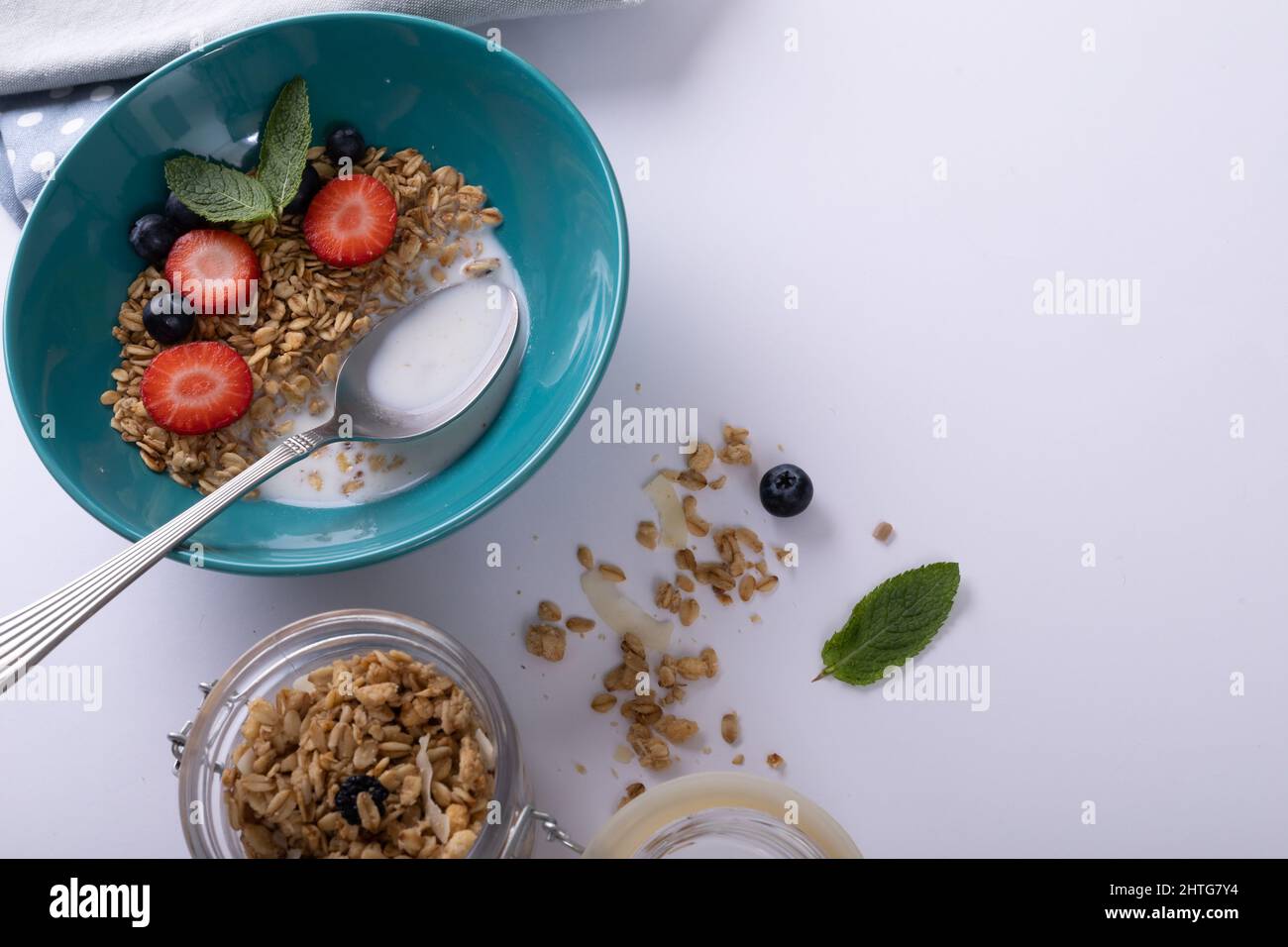 Gros plan de granola avec fruits aux baies, herbes et lait dans un bol avec une cuillère sur une table Banque D'Images